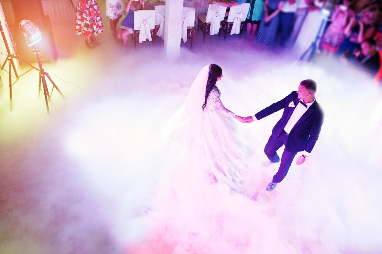 A couple is holding hands while dancing on the dance floor.