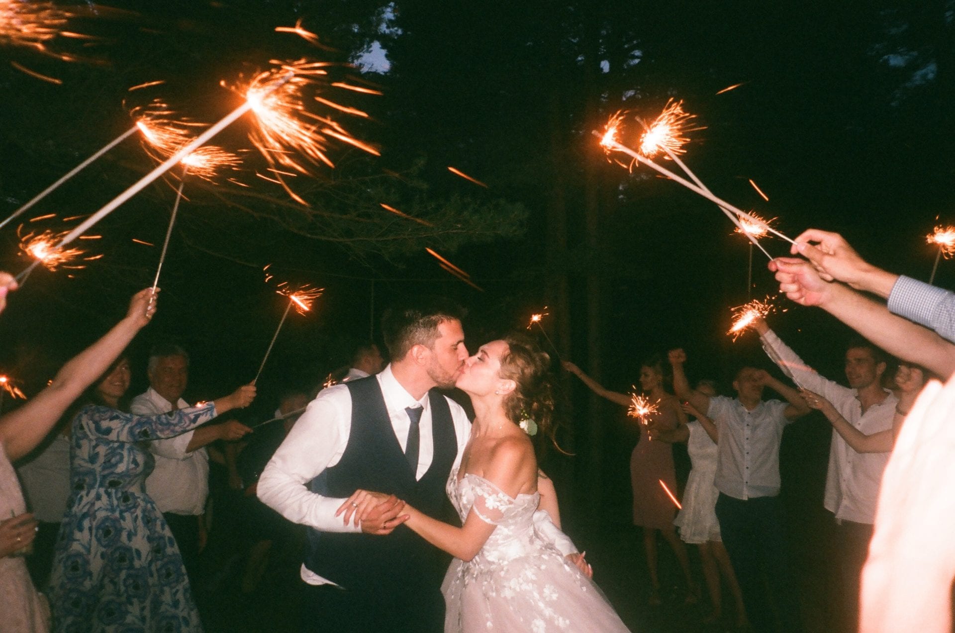 A couple kissing while holding sparklers in the air.